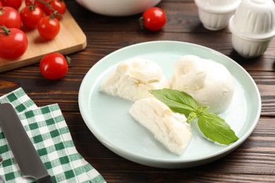 Photo of Delicious burrata cheese with basil served on wooden table