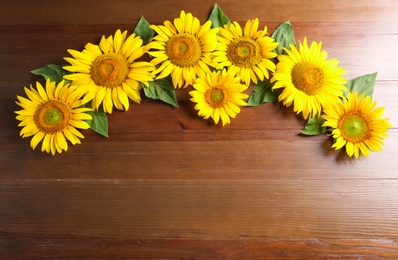 Photo of Beautiful bright sunflowers on wooden background, flat lay. Space for text