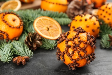 Photo of Pomander balls made of fresh tangerines with cloves  on dark table, closeup. Christmas atmosphere