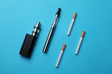 Photo of Electronic and regular cigarettes on light blue background, flat lay