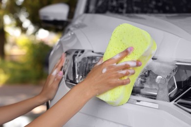 Photo of Woman washing car with sponge outdoors, closeup