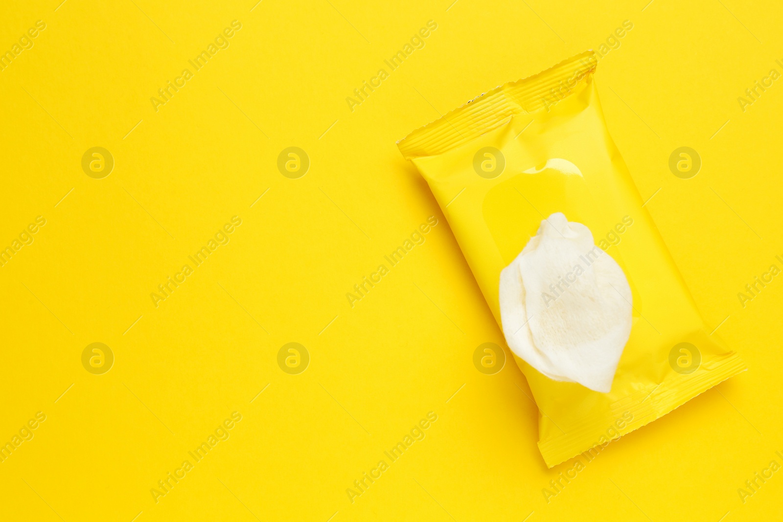 Photo of Wet wipes flow pack on yellow background, top view. Space for text