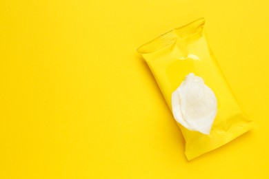 Photo of Wet wipes flow pack on yellow background, top view. Space for text