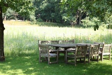 Photo of Empty wooden table with bench and chairs in garden