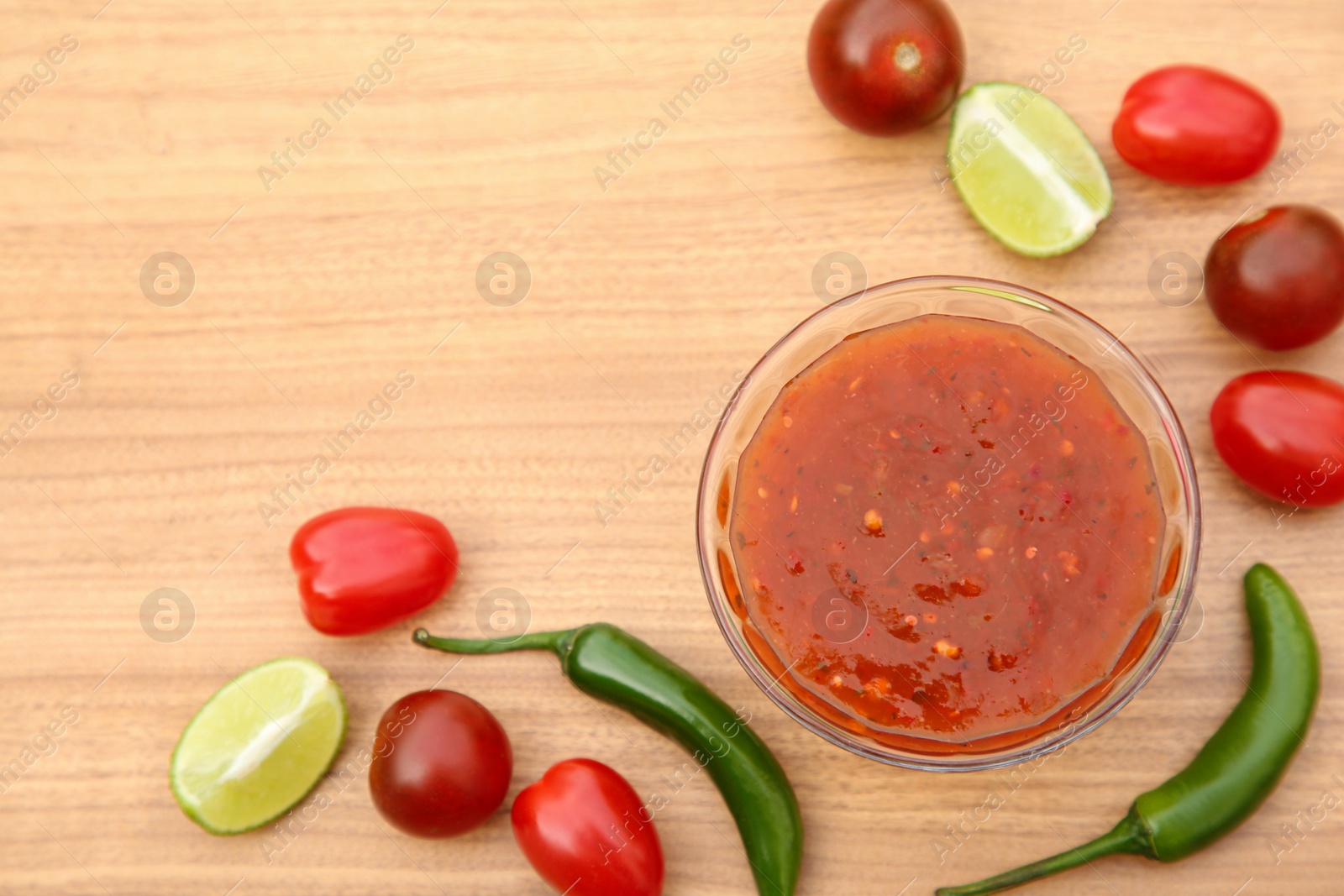 Photo of Flat lay composition of tasty salsa sauce and different ingredients on wooden table. Space for text