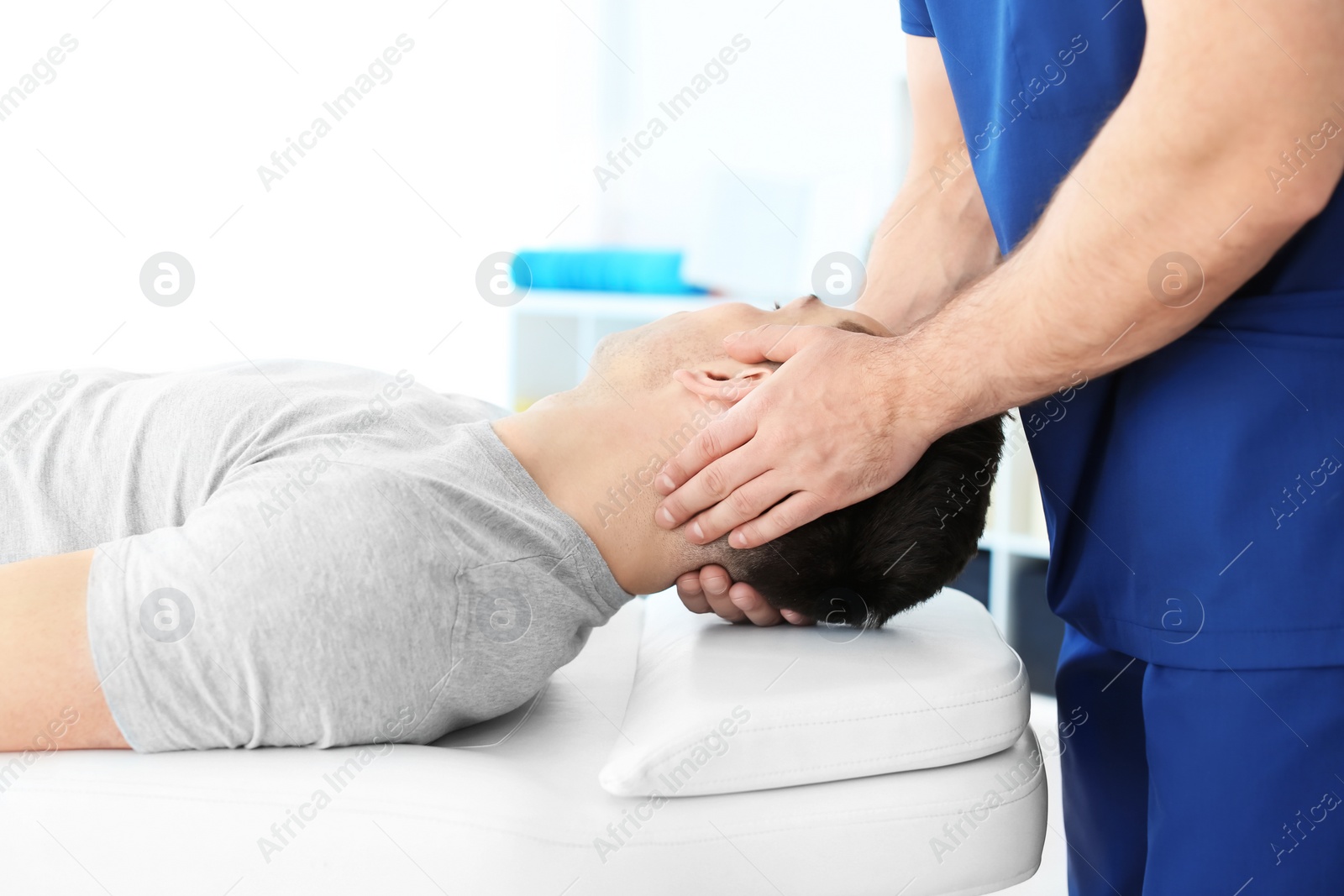 Photo of Physiotherapist working with young male patient in clinic