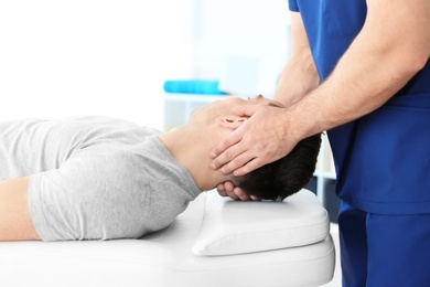 Photo of Physiotherapist working with young male patient in clinic