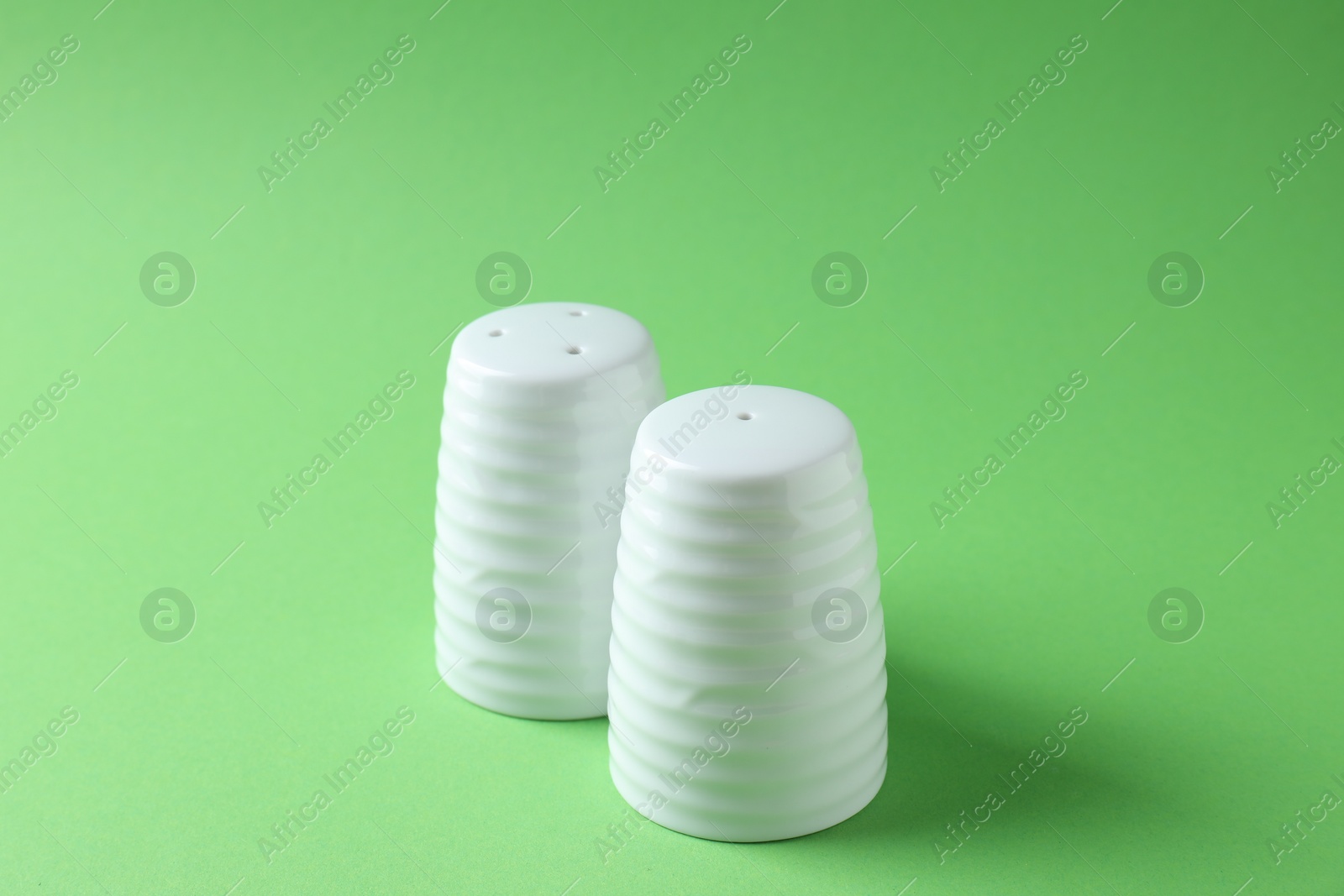 Photo of Salt and pepper shakers on green background