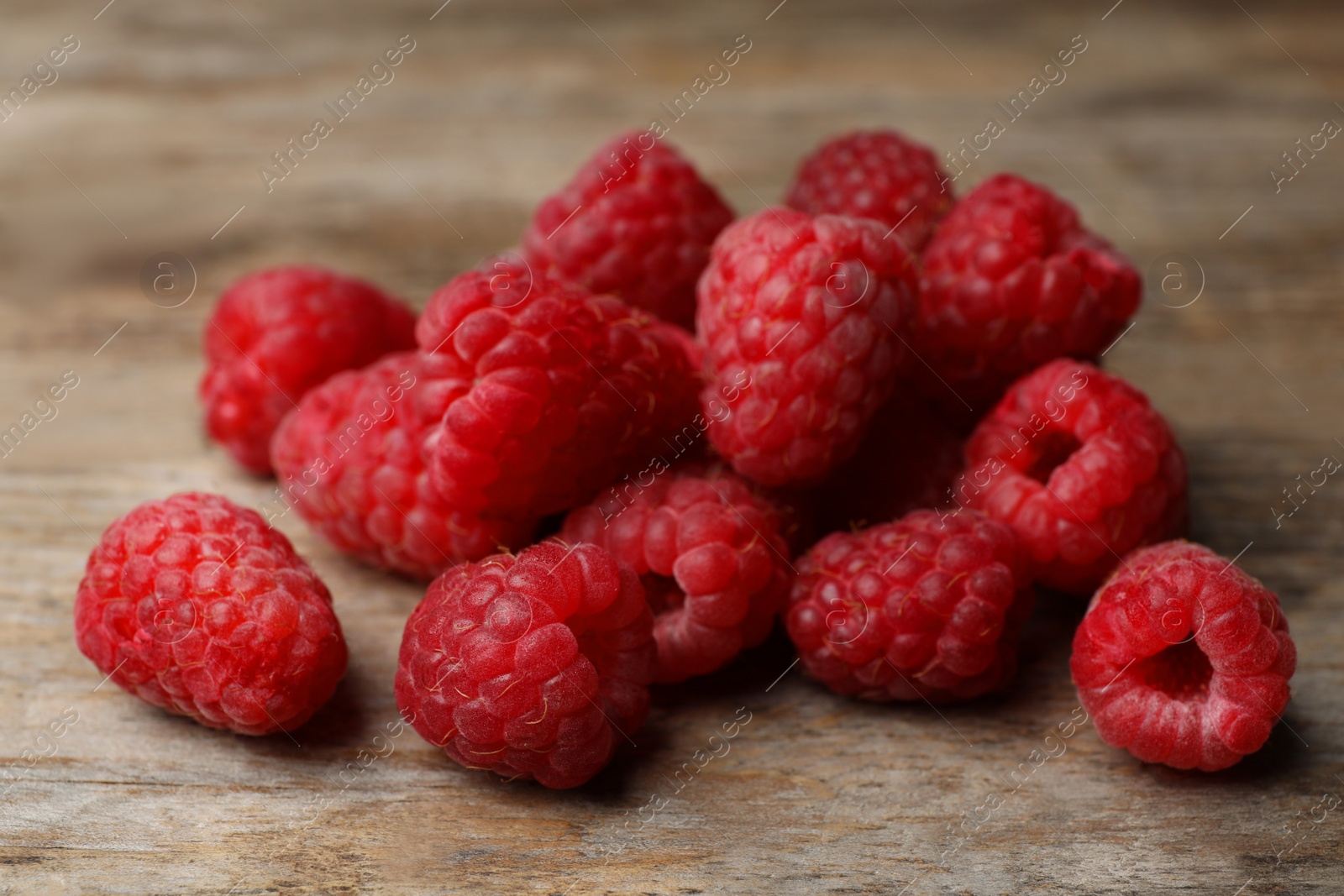 Photo of Heap of delicious ripe raspberries on wooden table, closeup