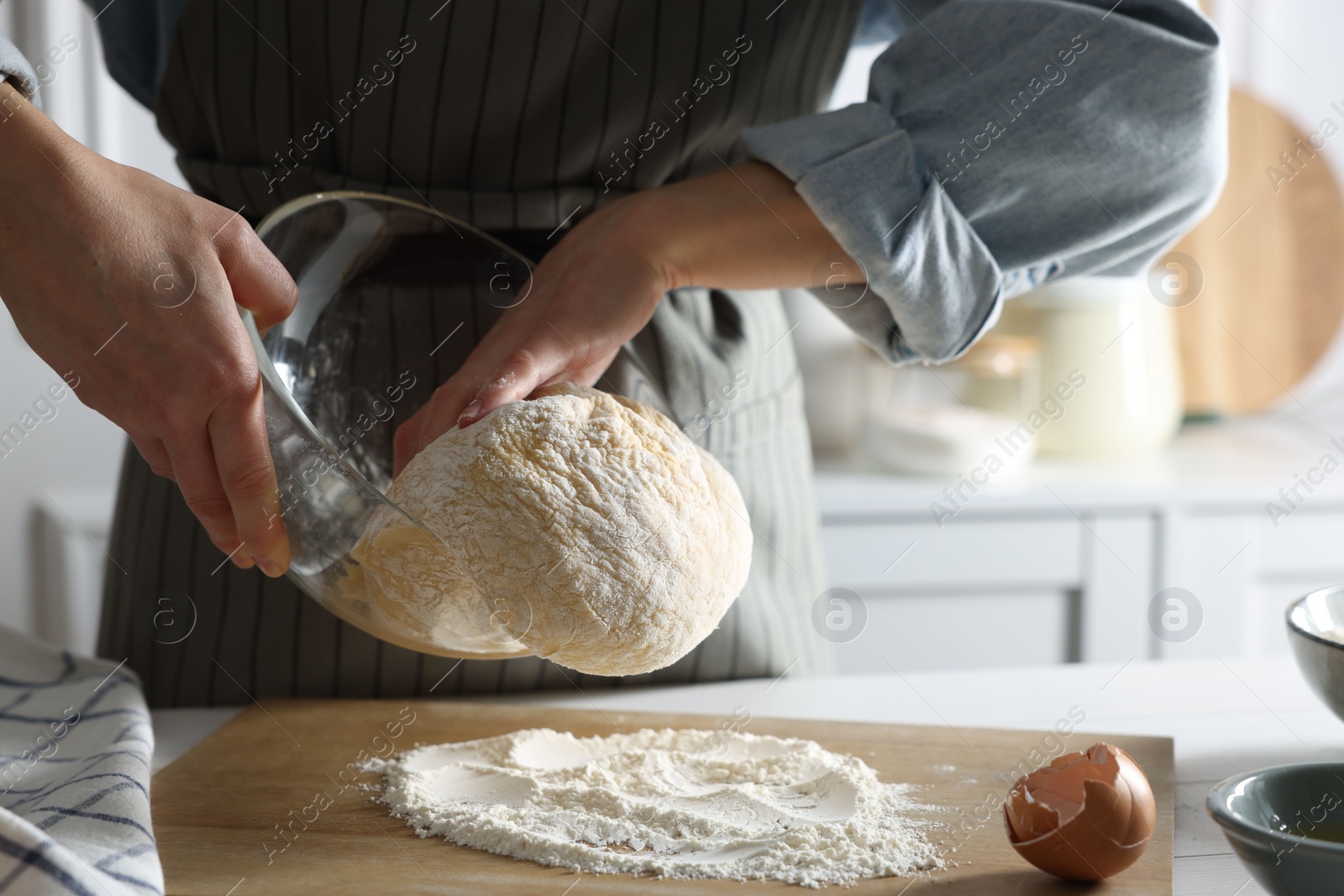 Photo of Woman kneading dough at white wooden table in kitchen, closeup