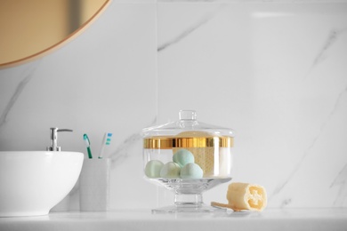 Photo of Jar with bath bombs and bath sponge on white countertop indoors