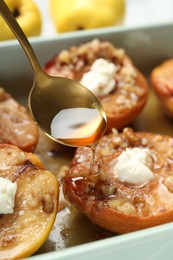 Pouring honey onto tasty baked quinces with nuts and cream cheese in dish, closeup