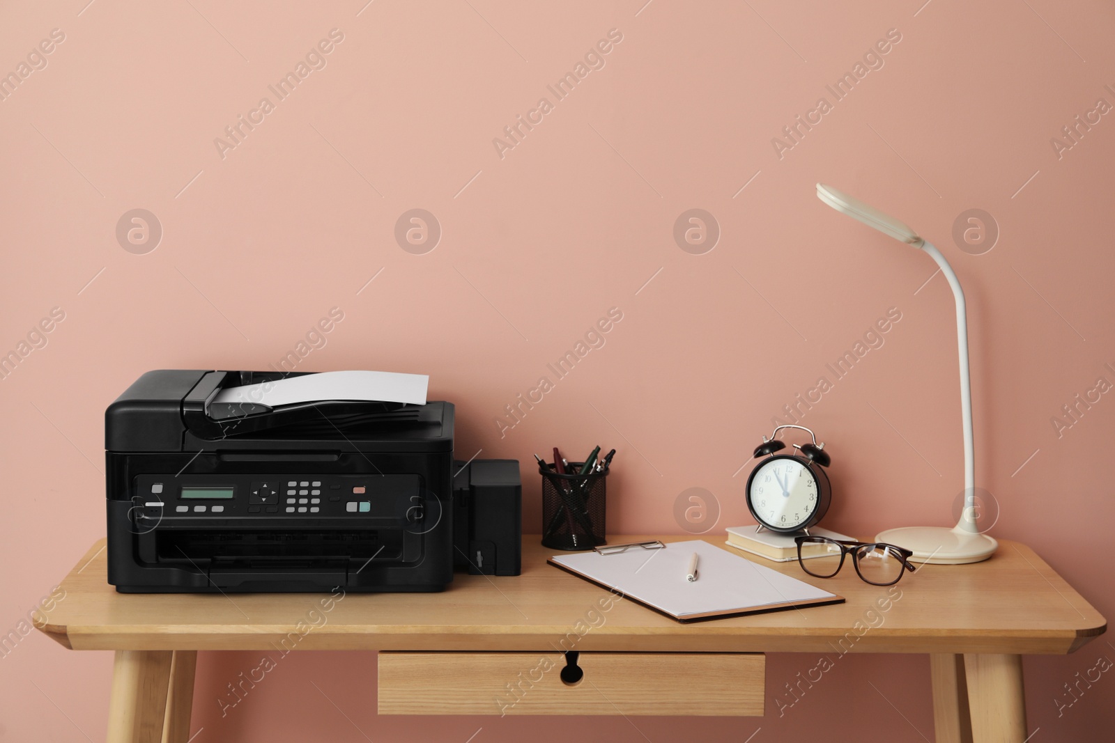 Photo of New modern printer and office supplies on wooden table