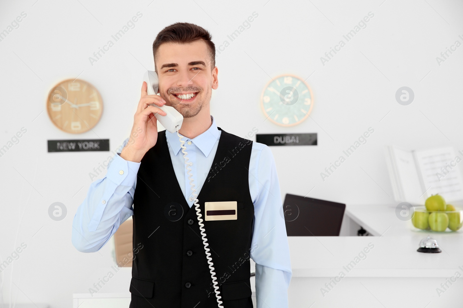 Photo of Male receptionist talking on phone at workplace in hotel