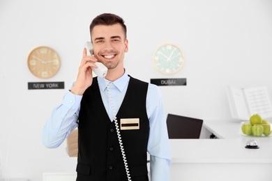 Male receptionist talking on phone at workplace in hotel