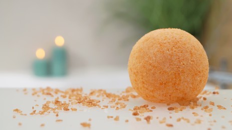 Photo of Orange bath bomb with salt on countertop near tub indoors, closeup. Space for text