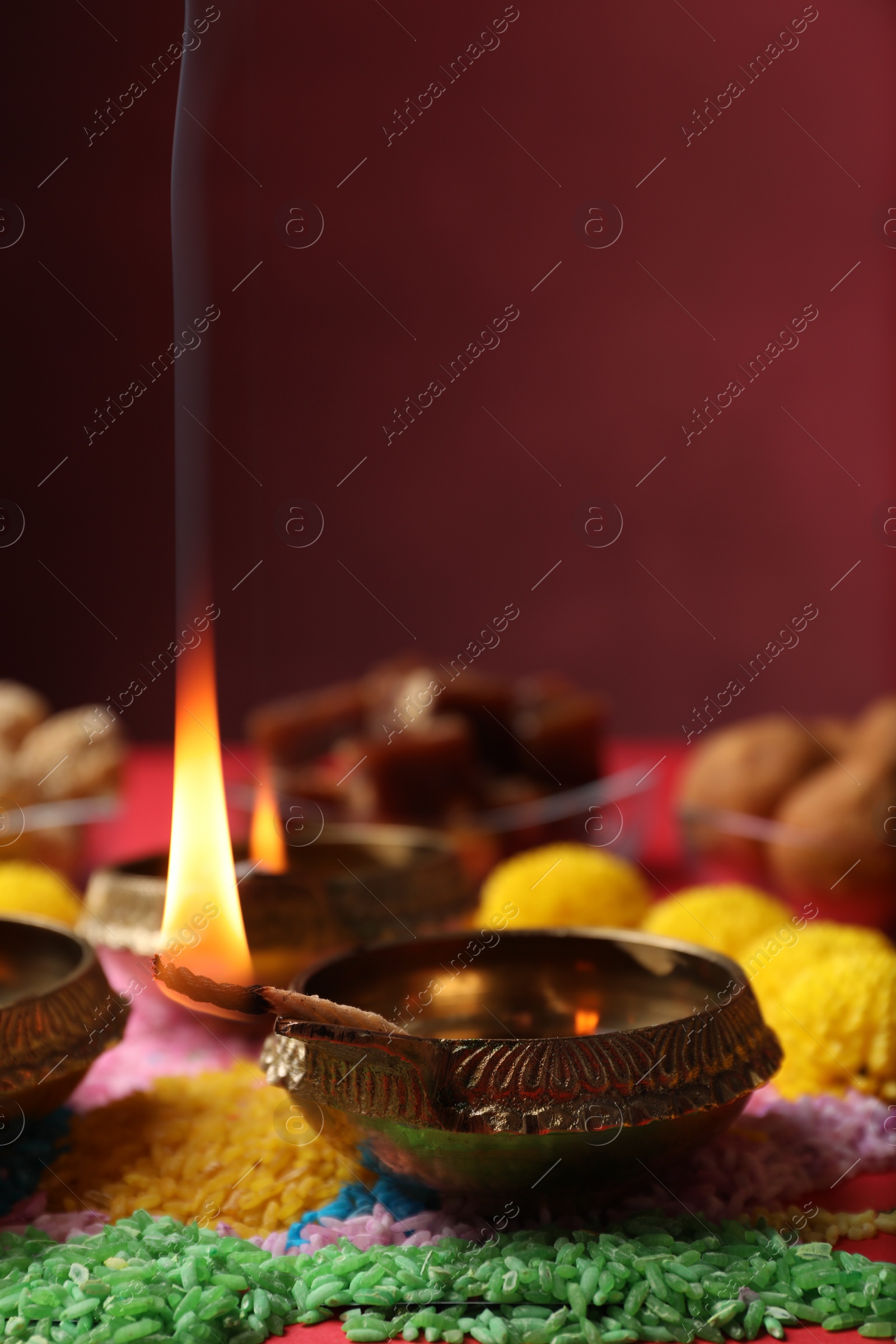 Photo of Diwali celebration. Diya lamps and colorful rangoli on red table, closeup. Space for text