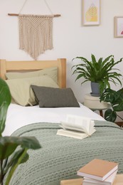 Large comfortable bed and potted houseplants in stylish bedroom. Interior design