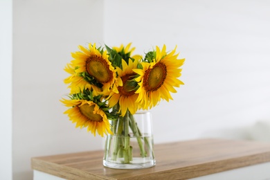 Beautiful yellow sunflowers on wooden table in room