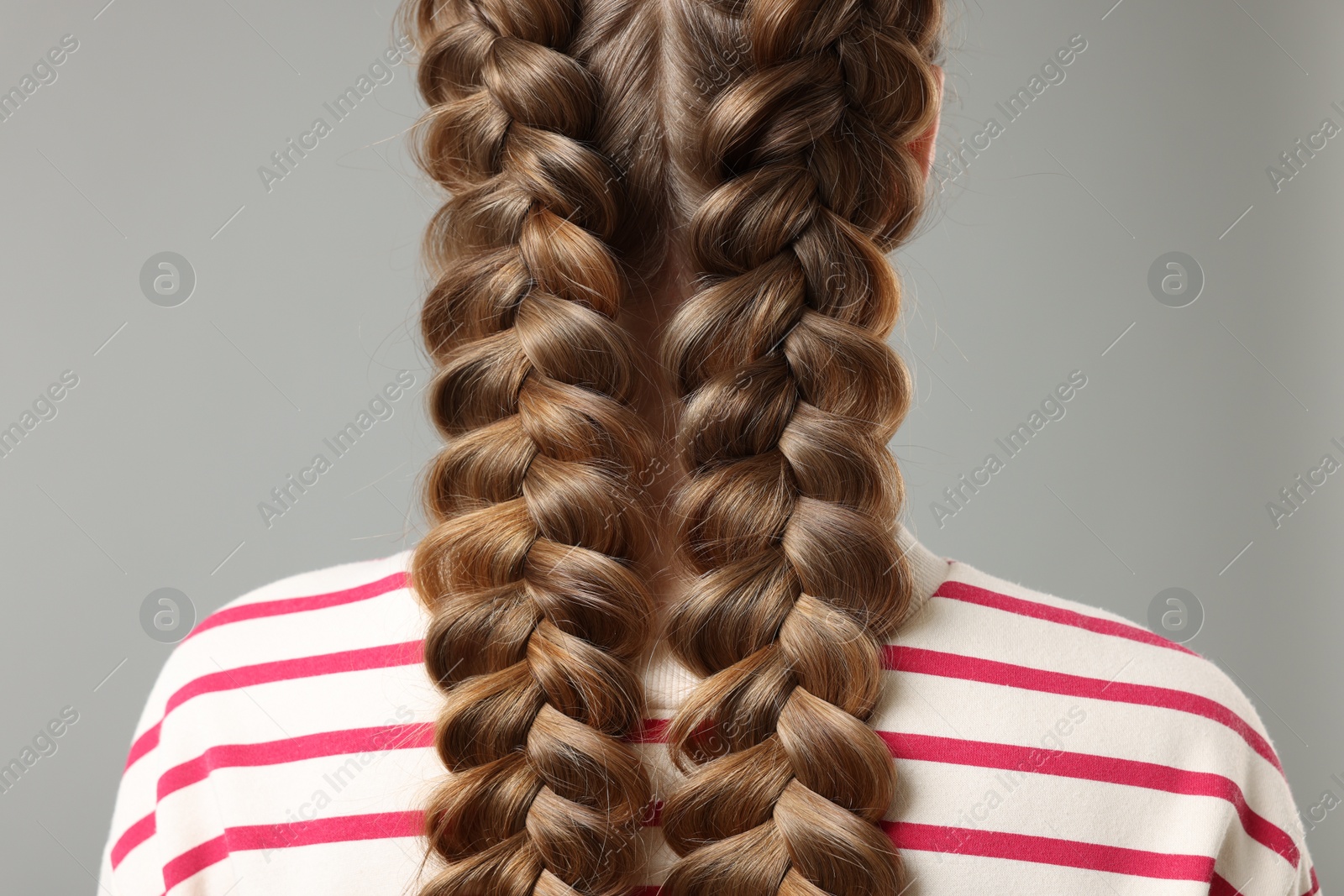 Photo of Woman with braided hair on grey background, closeup