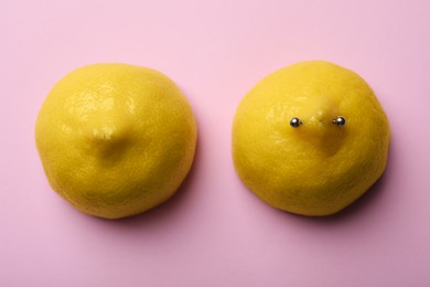 Photo of Yellow lemon halves with piercing on pink background, flat lay