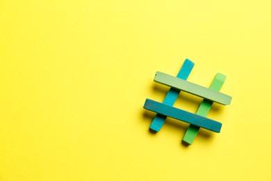 Photo of Hashtag symbol made of colorful chalks on yellow background, top view. Space for text