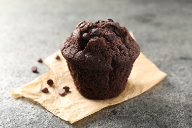 Photo of Delicious chocolate muffin on grey textured table, closeup