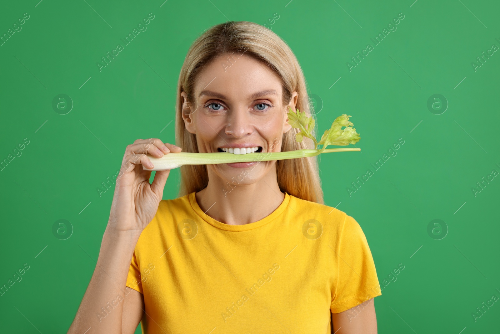 Photo of Woman eating fresh celery stem on green background