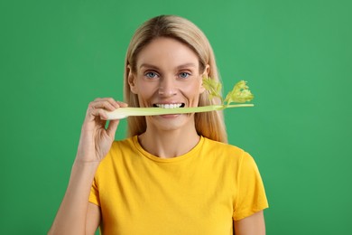 Photo of Woman eating fresh celery stem on green background