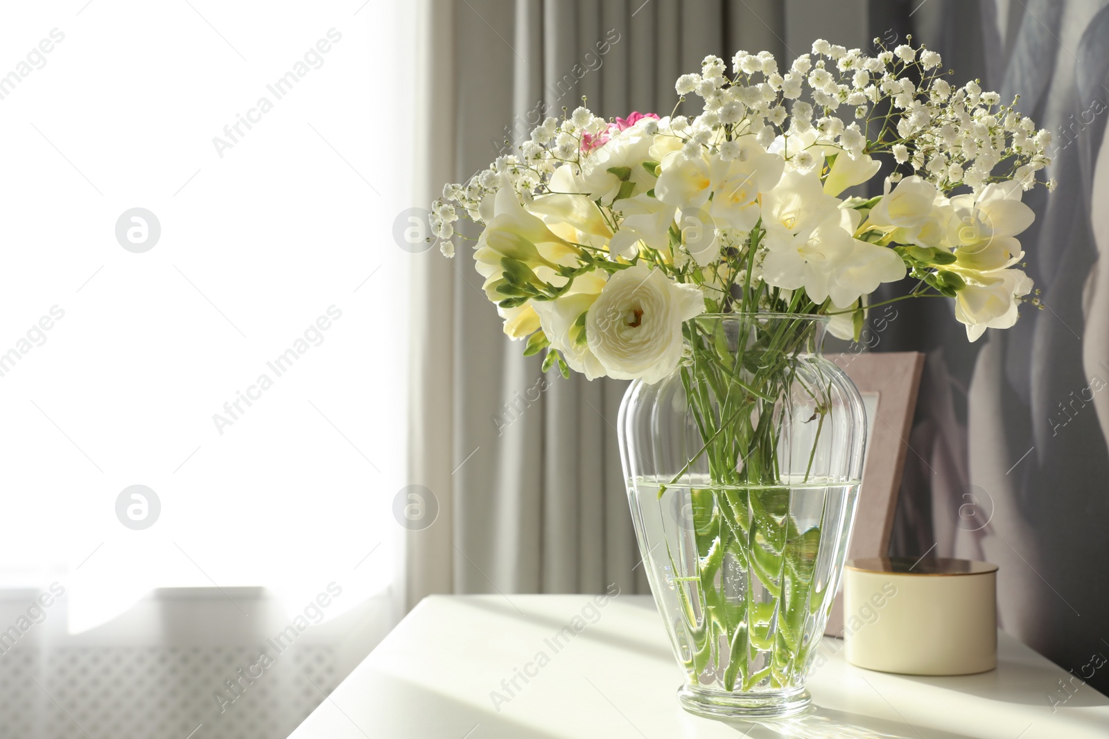 Photo of Beautiful bouquet with fresh freesia flowers in vase on table indoors. Space for text