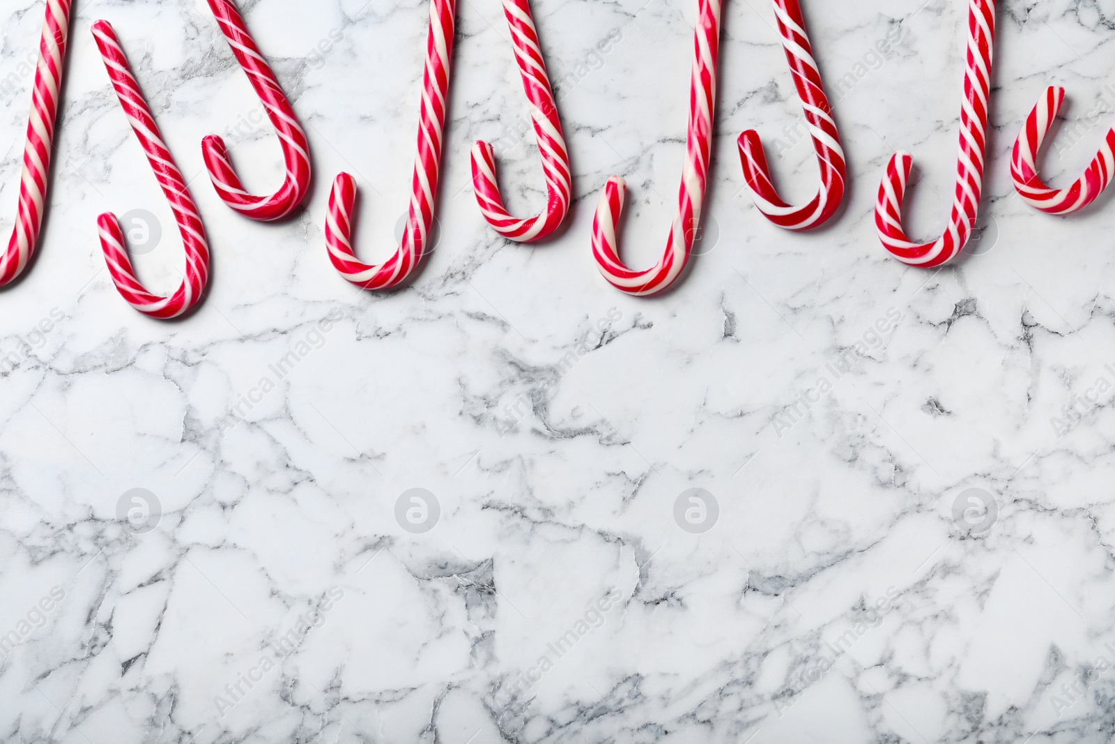 Photo of Sweet Christmas candy canes on white marble background, flat lay. Space for text
