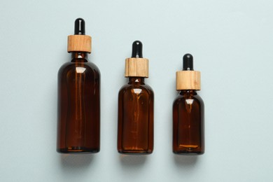 Photo of Bottles of face serum on light grey background, flat lay