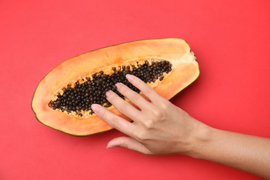 Photo of Young woman touching half of papaya on red background, top view. Sex concept