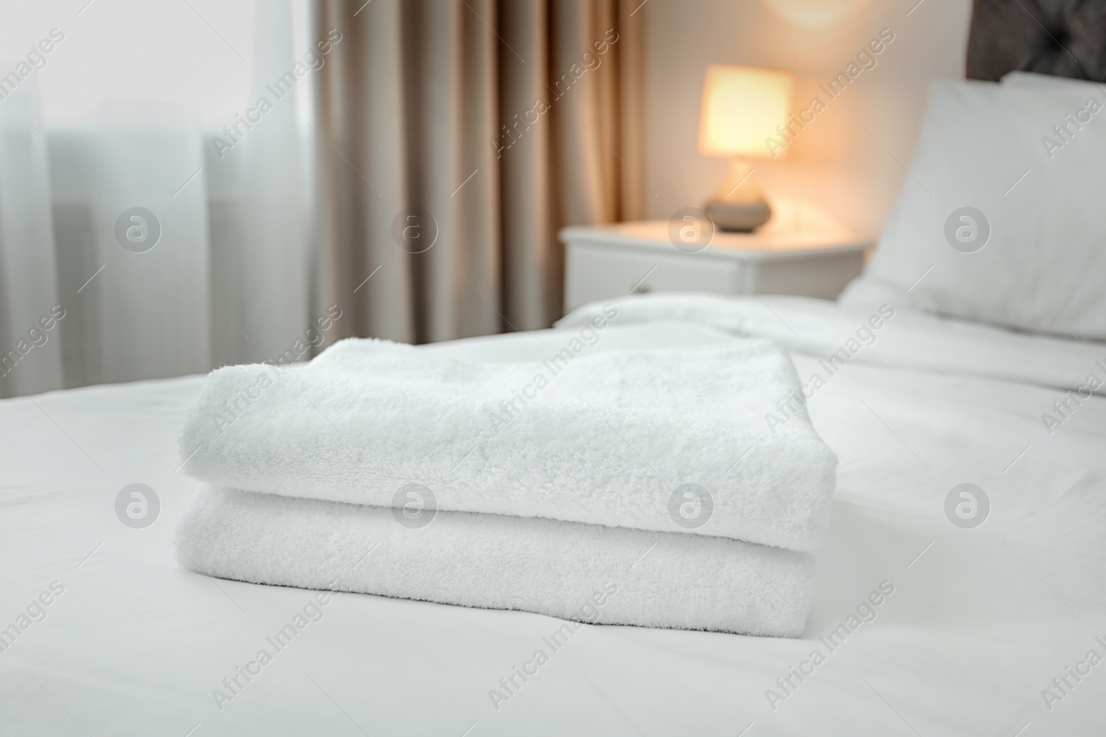 Photo of Stack of towels on bed in modern hotel room