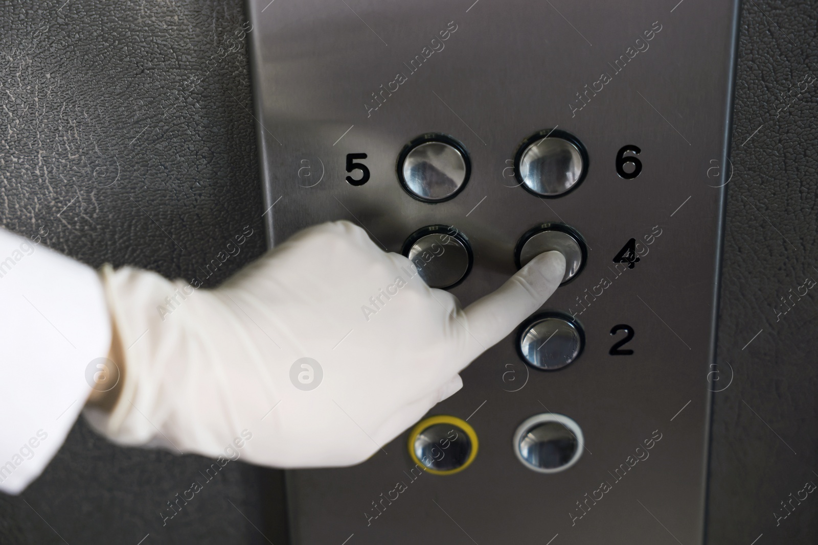 Photo of Woman wearing medical glove choosing floor in elevator, closeup. Protective measure