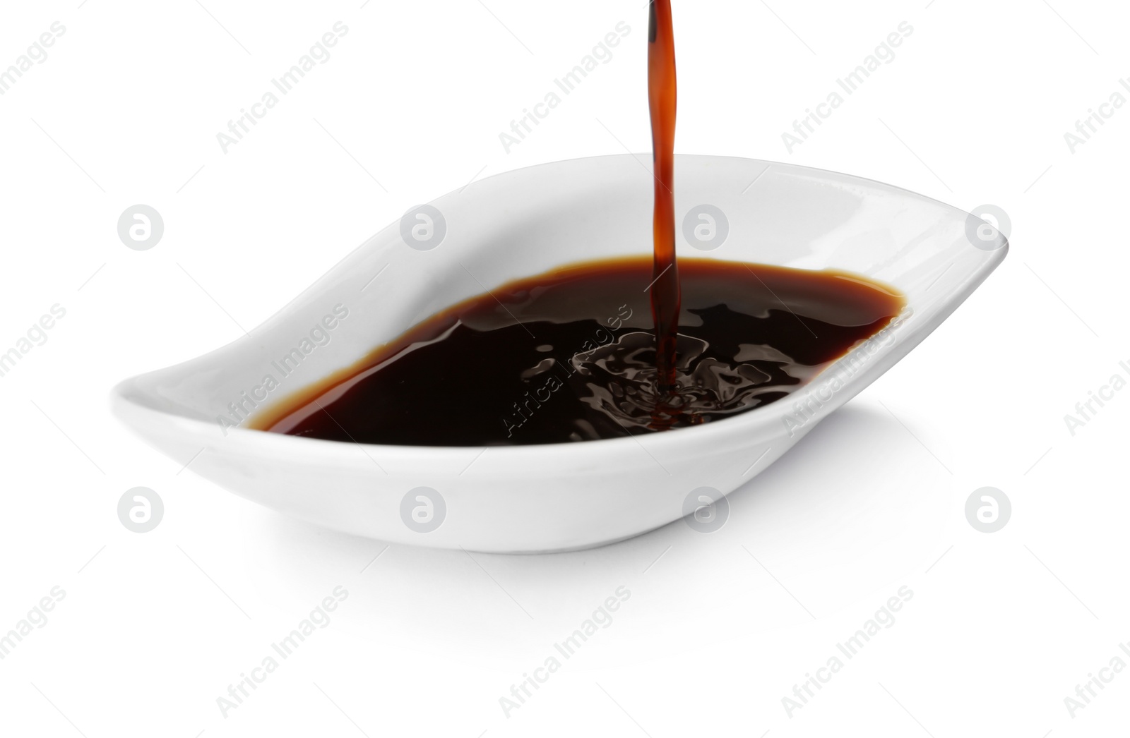 Photo of Pouring tasty soy sauce into bowl isolated on white