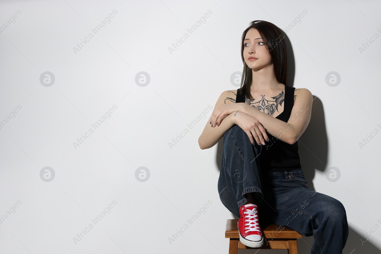 Photo of Portrait of beautiful tattooed woman on light background. Space for text