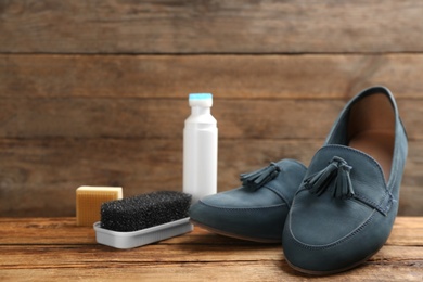 Stylish footwear with shoe care accessories on wooden table