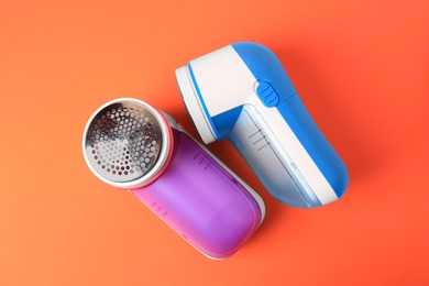 Different fabric shavers on orange background, top view