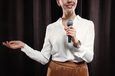 Motivational speaker with microphone performing on stage, closeup 
