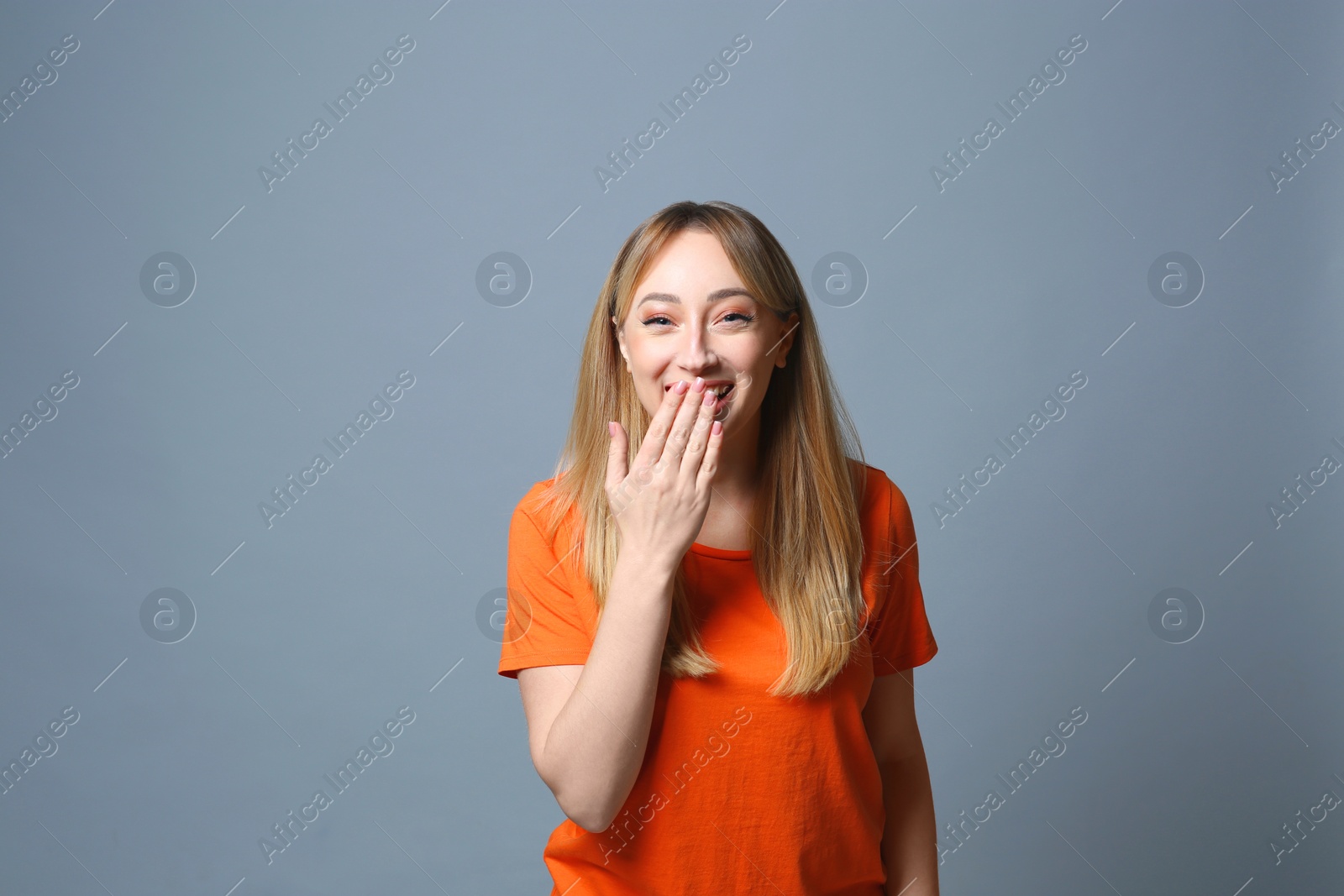 Photo of Beautiful young woman laughing on grey background. Funny joke