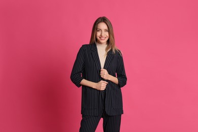 Portrait of beautiful young woman in fashionable suit on pink background. Business attire