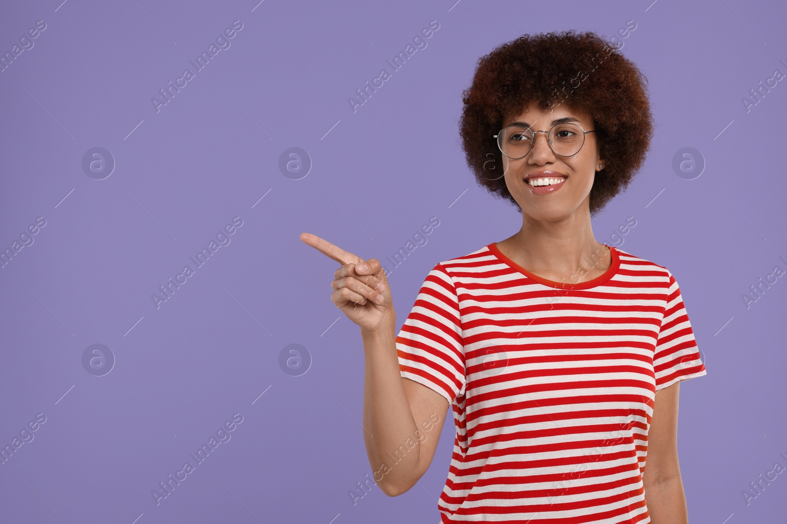 Photo of Happy young woman pointing at something on purple background. Space for text