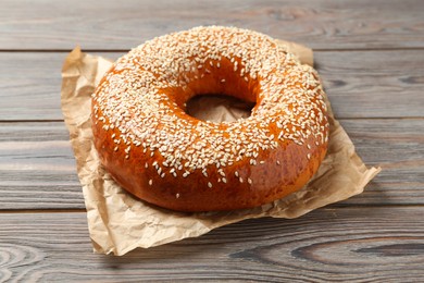 Photo of Delicious fresh bagel with sesame seeds on wooden table