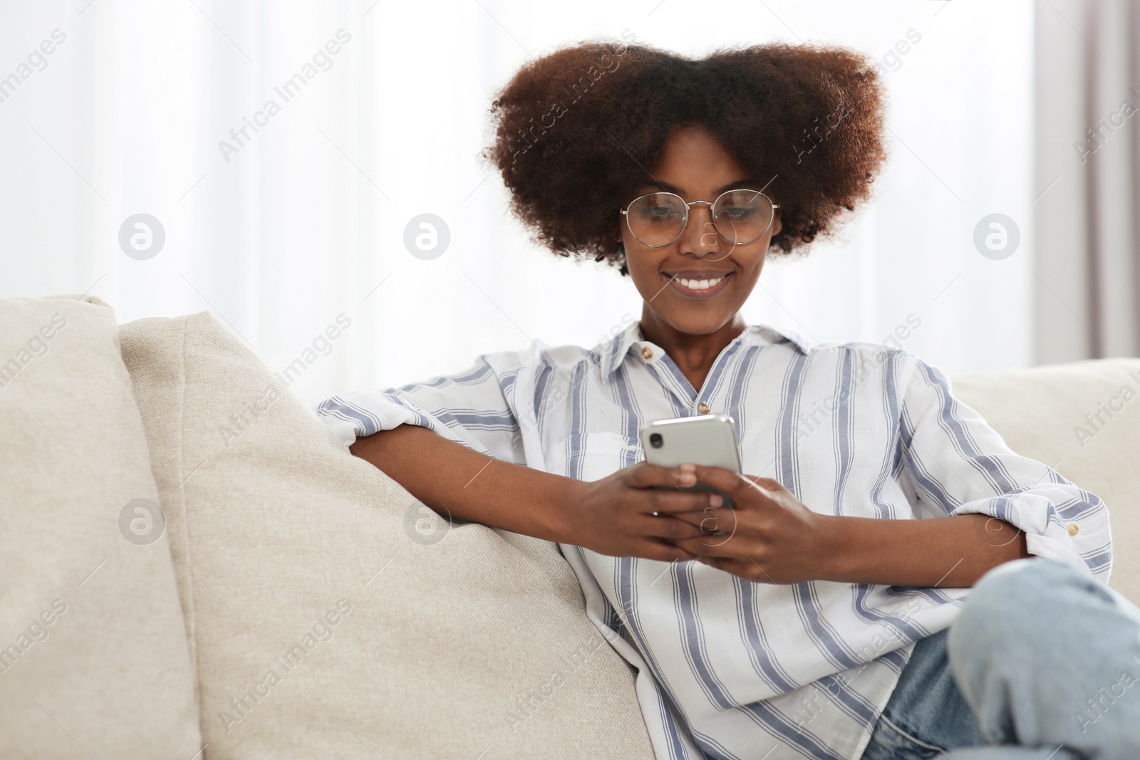 Photo of Smiling African American woman wearing glasses with smartphone at home. Space for text