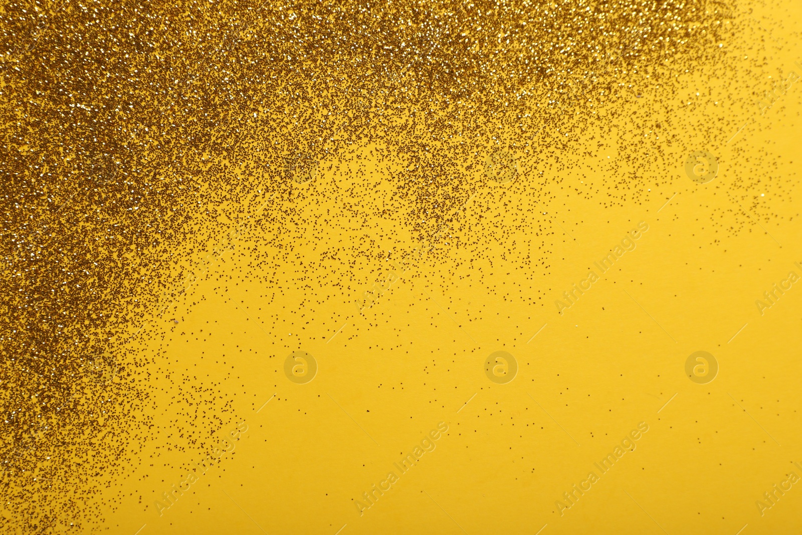 Photo of Shiny golden glitter on yellow background, top view. Space for text