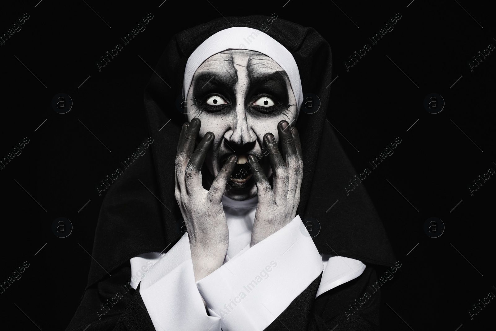 Photo of Portrait of scary devilish nun on black background. Halloween party look