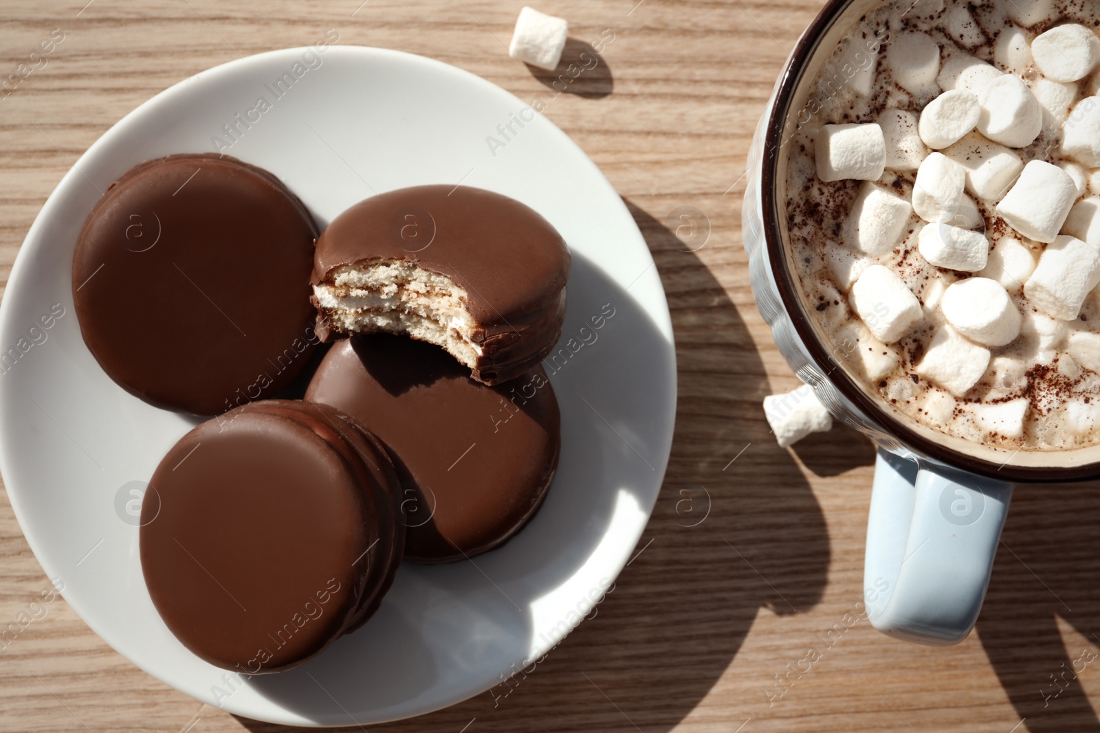Photo of Tasty choco pies and cocoa with marshmallows on wooden table, flat lay