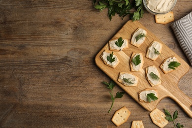 Delicious crackers with humus, parsley and dill on wooden table, flat lay. Space for text