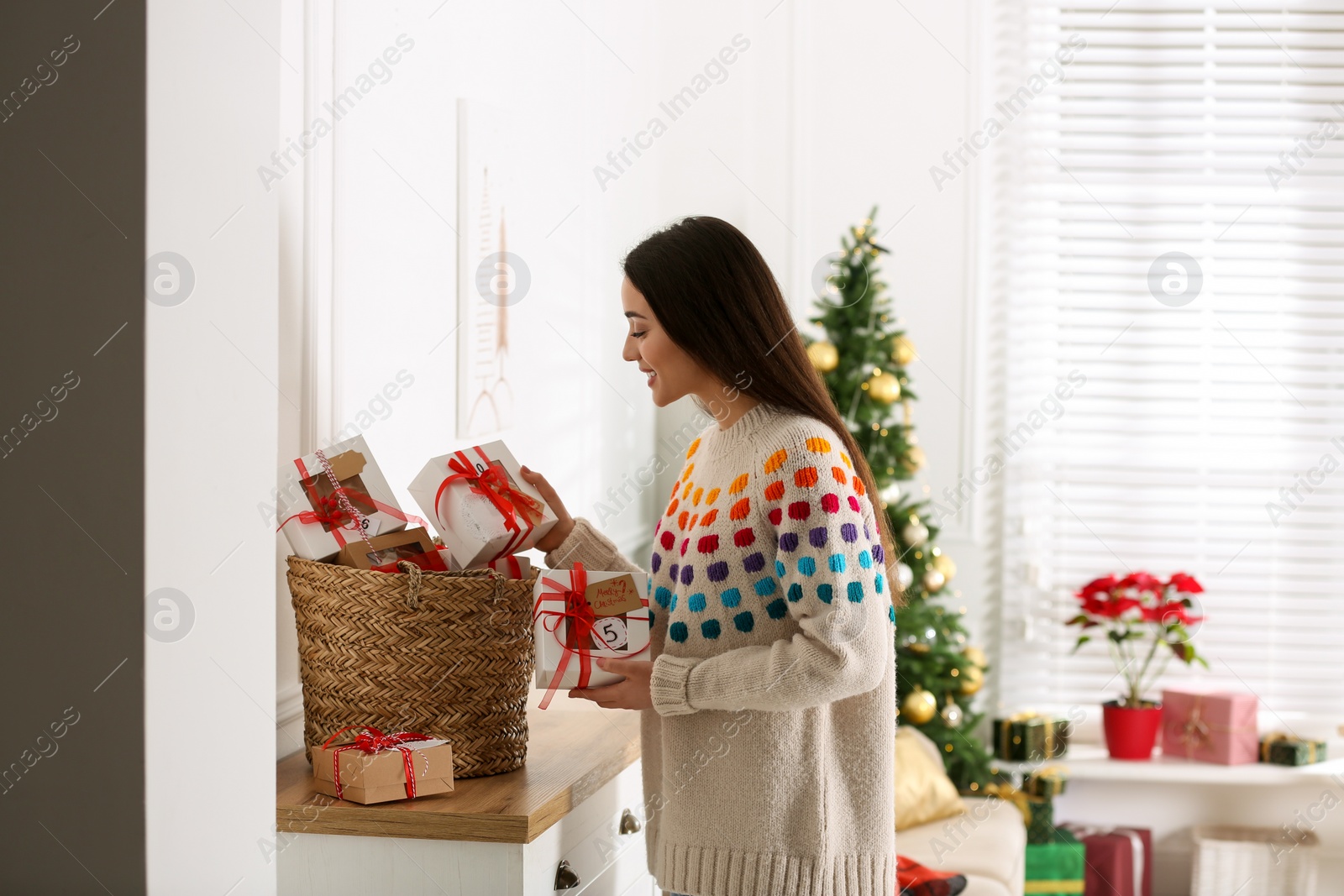 Photo of Woman with Christmas gifts at home. Advent calendar in basket